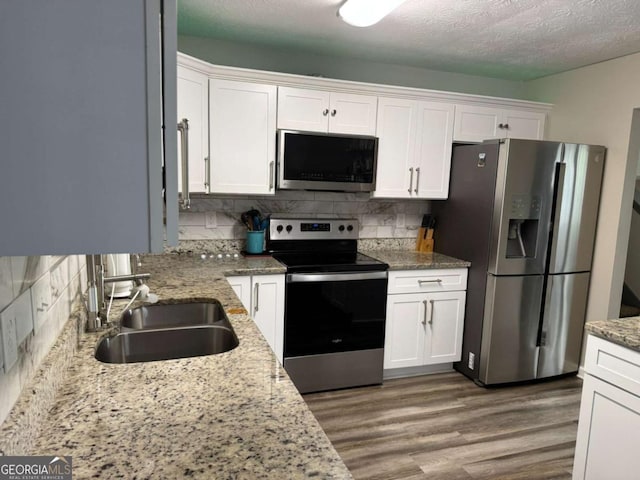 4678 Browns Mill Ferry Rd, Lithonia, GA 30038 - kitchen with appliances with stainless steel finishes, a sink, white cabinetry, wood finished floors, and decorative backsplash