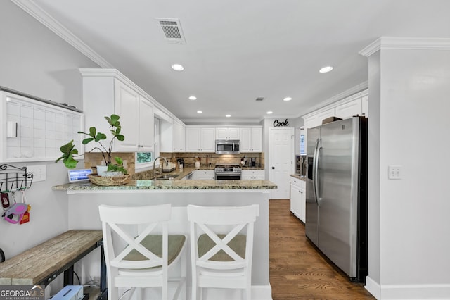 3535 Fairgreen Ct, Douglasville, GA 30135 - kitchen with appliances with stainless steel finishes, a peninsula, white cabinetry, a sink, and crown molding