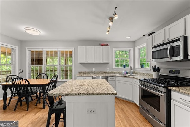 5510 Pilgrim Point Ext, Cumming, GA 30041 - kitchen with appliances with stainless steel finishes, a sink, a kitchen island, a breakfast bar, and white cabinetry