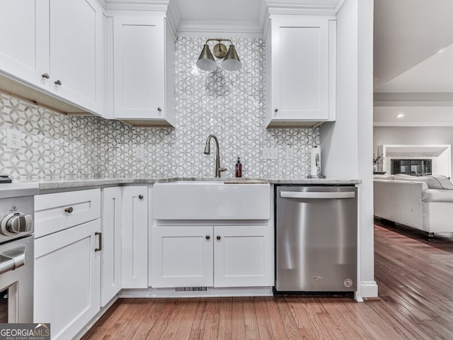 646 Darlington Cir NE, Atlanta, GA 30305 - kitchen with stainless steel dishwasher, a sink, light countertops, light wood-type flooring, and white cabinets