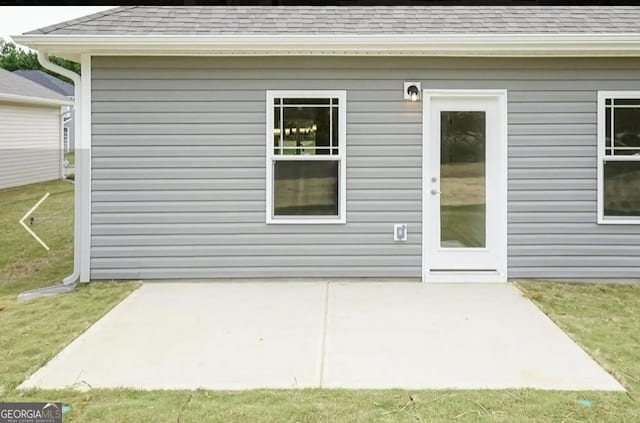 584 Walnut Creek Pkwy, Pendergrass, GA 30567 - entrance to property featuring roof with shingles, a patio area, and a lawn