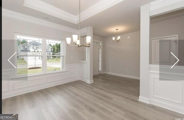 584 Walnut Creek Pkwy, Pendergrass, GA 30567 - unfurnished dining area featuring a chandelier, light wood finished floors, a raised ceiling, ornamental molding, and a decorative wall