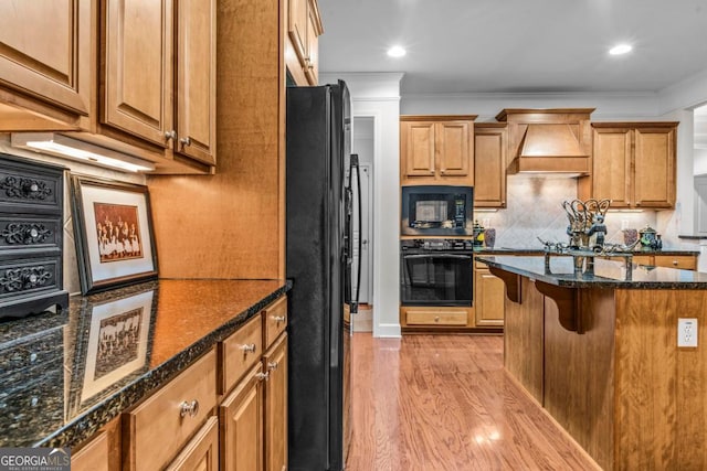 1000 Deep Water Way, Greensboro, GA 30642 - kitchen featuring black appliances, custom range hood, light wood-style floors, a breakfast bar area, and backsplash