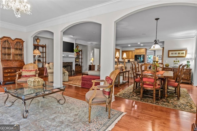 1000 Deep Water Way, Greensboro, GA 30642 - living area with light wood-type flooring, crown molding, a premium fireplace, arched walkways, and recessed lighting