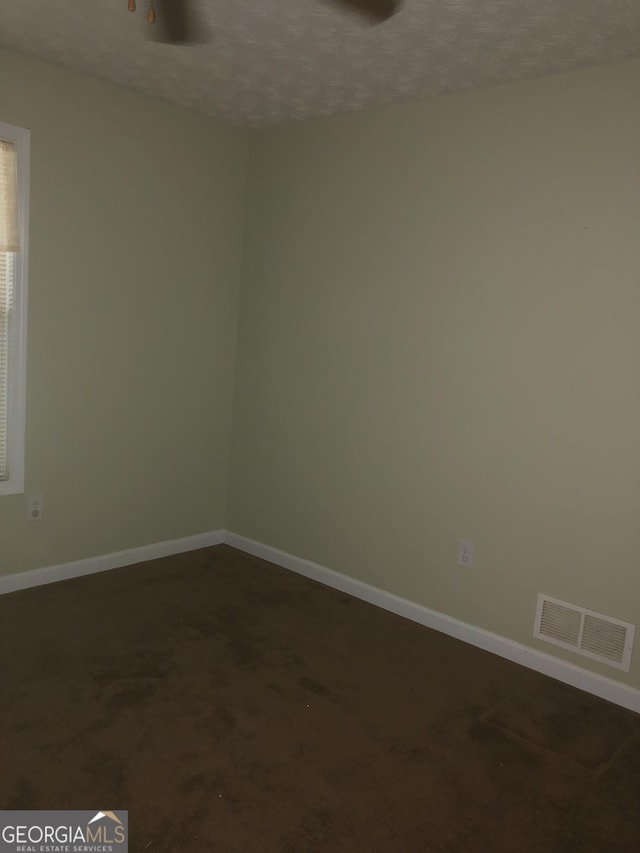 1744 Campbell Rd, Covington, GA 30014 - unfurnished room with baseboards, a textured ceiling, and dark carpet