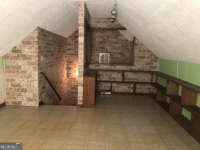 1744 Campbell Rd, Covington, GA 30014 - additional living space with a textured ceiling, vaulted ceiling, tile patterned floors, and brick wall