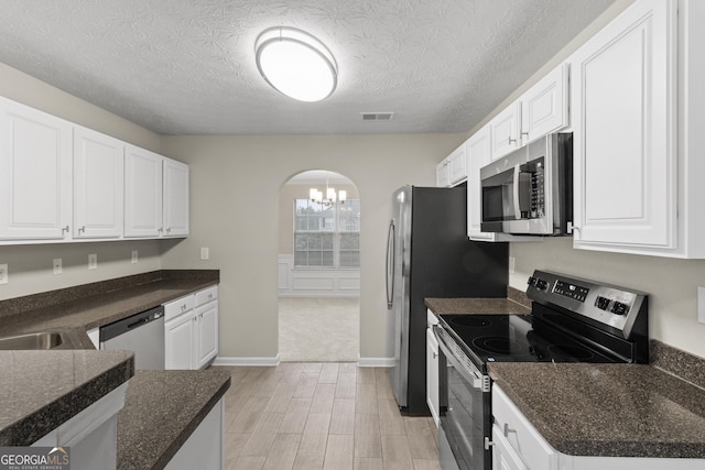 165 Heaton Place Trl, Covington, GA 30016 - kitchen featuring appliances with stainless steel finishes, arched walkways, a chandelier, white cabinets, and light wood-style flooring