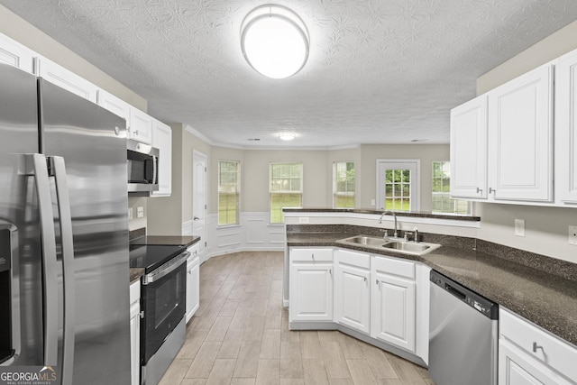 165 Heaton Place Trl, Covington, GA 30016 - kitchen featuring appliances with stainless steel finishes, a sink, white cabinets, wainscoting, and a textured ceiling