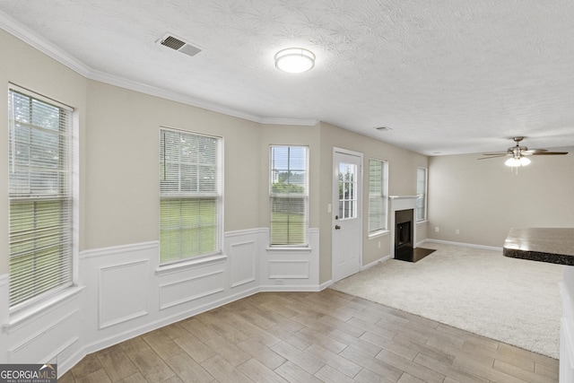 165 Heaton Place Trl, Covington, GA 30016 - unfurnished living room with light wood-type flooring, wainscoting, a fireplace with flush hearth, ornamental molding, and ceiling fan
