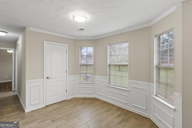 165 Heaton Place Trl, Covington, GA 30016 - unfurnished dining area with light wood-style flooring, wainscoting, a textured ceiling, and crown molding
