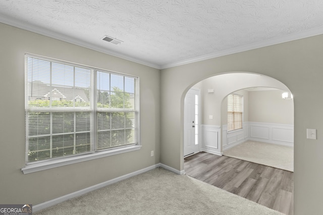 165 Heaton Place Trl, Covington, GA 30016 - spare room with arched walkways, a textured ceiling, crown molding, wood finished floors, and a wainscoted wall