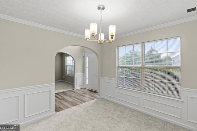 165 Heaton Place Trl, Covington, GA 30016 - unfurnished dining area with a wainscoted wall, arched walkways, a chandelier, carpet floors, and crown molding