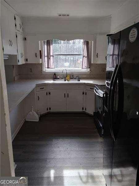 4076 Fairmont St, Gainesville, GA 30506 - kitchen with black fridge with ice dispenser, stove, white cabinets, light countertops, and dark wood-style flooring