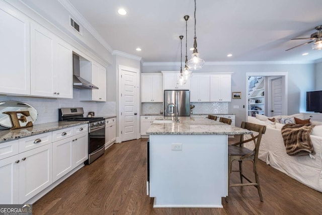 1753 Russell St SE, Atlanta, GA 30316 - kitchen featuring stainless steel appliances, wall chimney exhaust hood, a kitchen breakfast bar, crown molding, and white cabinets