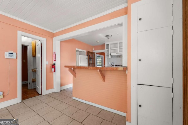 3956 Tell Rd SW, Atlanta, GA 30331 - kitchen featuring freestanding refrigerator, a kitchen breakfast bar, light tile patterned floors, crown molding, and under cabinet range hood