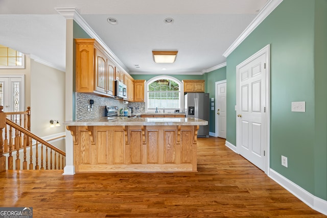 894 Oak Pointe Dr, Cleveland, GA 30528 - kitchen with stainless steel appliances, a peninsula, wood finished floors, ornamental molding, and light countertops