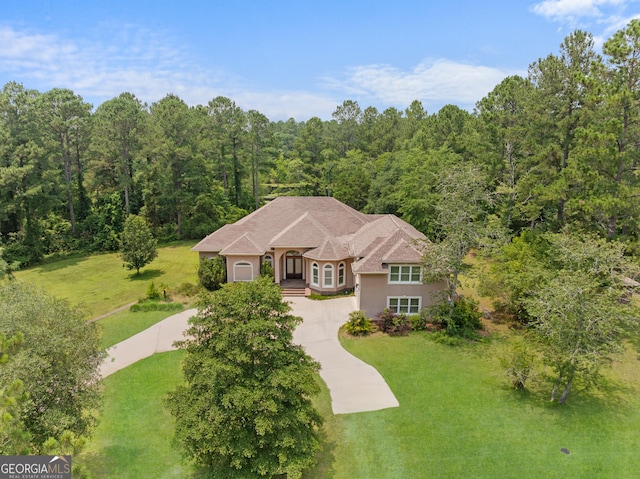353 Indigo Hills Rd, Pembroke, GA 31321 - view of front of house featuring a front lawn, driveway, stucco siding, and a forest view