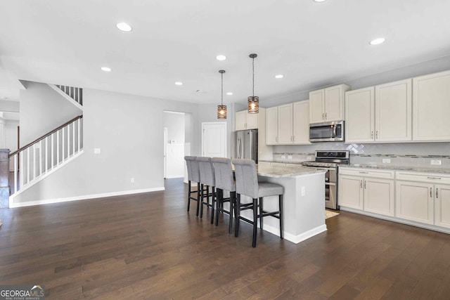 2029 Havenhurst Way, Auburn, GA 30011 - kitchen with stainless steel appliances, a kitchen bar, dark wood finished floors, a kitchen island, and hanging light fixtures