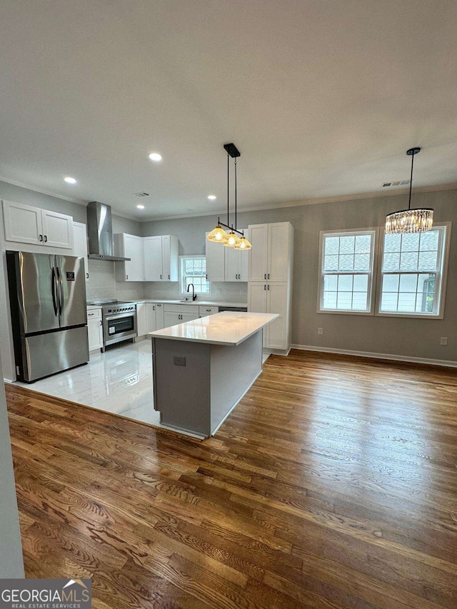 1766 W Lyle Ave, College Park, GA 30337 - kitchen featuring wall chimney range hood, stainless steel appliances, wood finished floors, a sink, and white cabinets