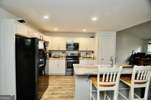 1040 Matthew Ln, Madison, GA 30650 - kitchen featuring stainless steel appliances, white cabinets, light wood finished floors, recessed lighting, and a breakfast bar
