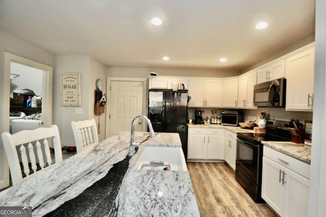 1040 Matthew Ln, Madison, GA 30650 - kitchen featuring black appliances, white cabinetry, light wood-style flooring, light stone countertops, and recessed lighting