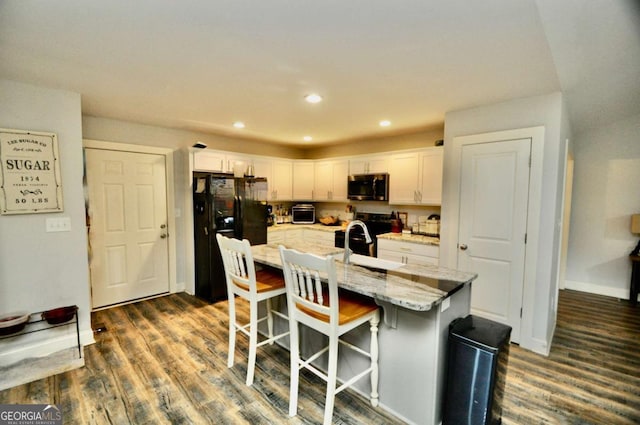 1040 Matthew Ln, Madison, GA 30650 - kitchen featuring black appliances, dark wood-style floors, white cabinets, a sink, and a kitchen bar