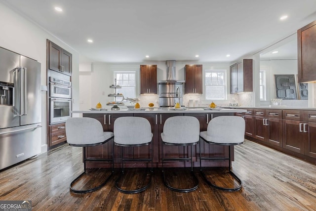 937 Rosedale Rd NE, Atlanta, GA 30306 - kitchen featuring appliances with stainless steel finishes, wall chimney exhaust hood, a kitchen bar, wood finished floors, and decorative backsplash