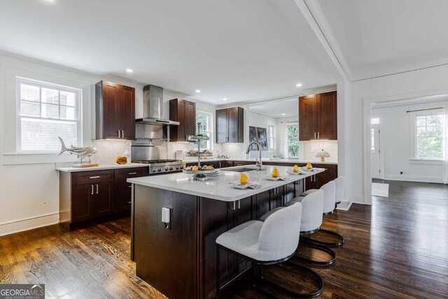 937 Rosedale Rd NE, Atlanta, GA 30306 - kitchen featuring wall chimney exhaust hood, a kitchen breakfast bar, light countertops, dark wood-style flooring, and backsplash