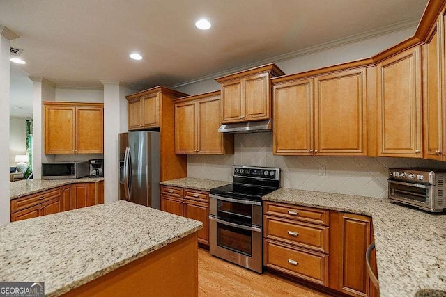 1901 Franklin Grove Pkwy, Bogart, GA 30622 - kitchen featuring stainless steel appliances, crown molding, under cabinet range hood, brown cabinets, and light stone countertops