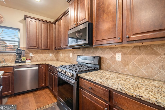 817 Nevis Way, Mcdonough, GA 30253 - kitchen featuring appliances with stainless steel finishes, light stone counters, decorative backsplash, light wood-style floors, and a sink