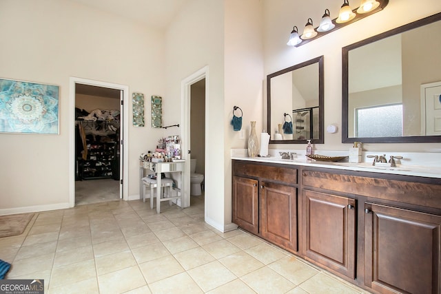 817 Nevis Way, Mcdonough, GA 30253 - bathroom with a towering ceiling, toilet, double vanity, a spacious closet, and tile patterned floors