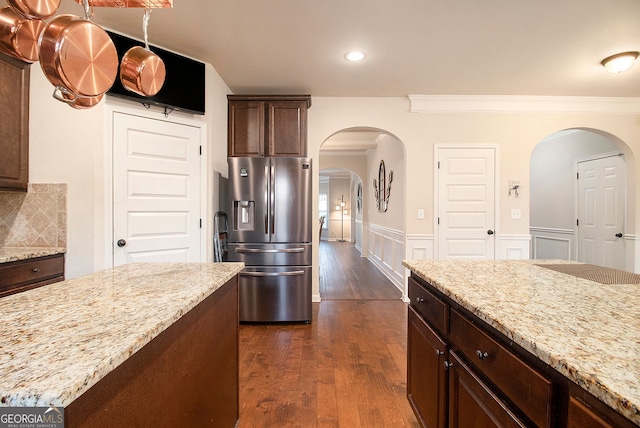 817 Nevis Way, Mcdonough, GA 30253 - kitchen featuring stainless steel fridge with ice dispenser, arched walkways, light stone counters, dark wood-type flooring, and crown molding