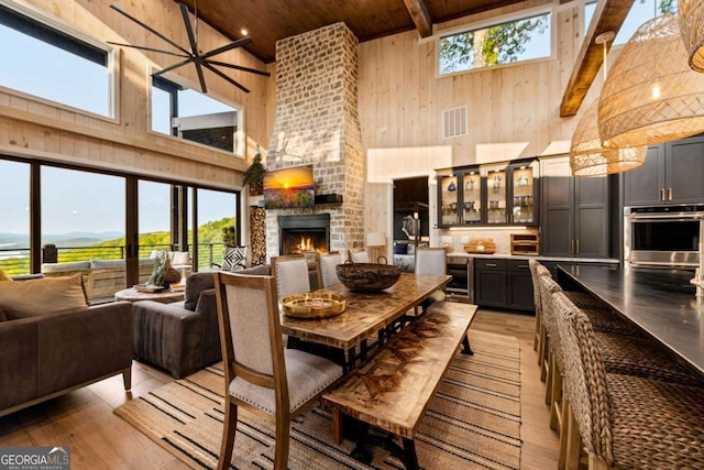 719 Ripshin Mountain Rd, Blue Ridge, GA 30513 - dining room with a towering ceiling, wood ceiling with exposed beams, wine cooler, a fireplace, and light wood-style floors