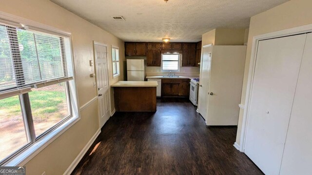 2015 Corners Cir, Lithonia, GA 30058 - kitchen with white appliances, dark wood-type flooring, light countertops, a peninsula, and a textured ceiling
