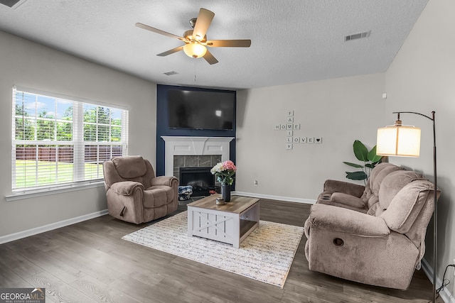 26 NE Sunflower Cir, Ludowici, GA 31316 - living room featuring a textured ceiling, a ceiling fan, a tile fireplace, baseboards, and dark wood-style floors