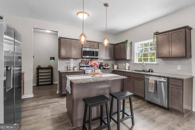 26 NE Sunflower Cir, Ludowici, GA 31316 - kitchen featuring appliances with stainless steel finishes, a sink, light wood-type flooring, a center island, and a textured ceiling