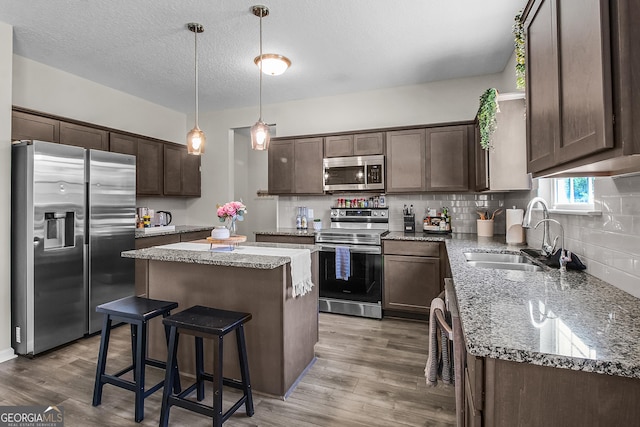 26 NE Sunflower Cir, Ludowici, GA 31316 - kitchen with stainless steel appliances, a sink, dark brown cabinetry, a center island, and light wood-style flooring