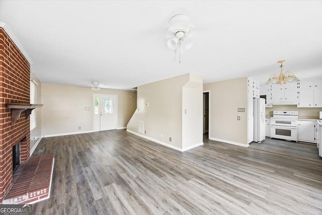 437 Edgewater Cir, Macon, GA 31220 - unfurnished living room featuring a chandelier, a brick fireplace, wood finished floors, and baseboards