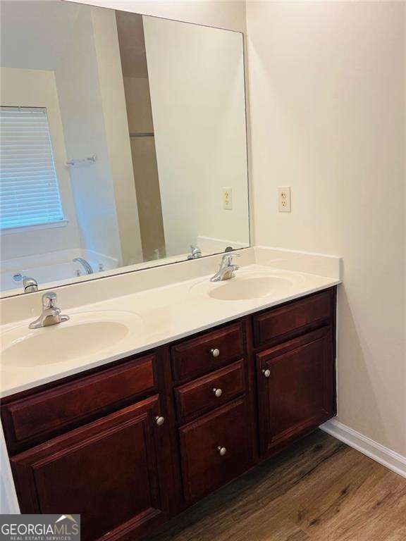 5123 Upper Elm St, Atlanta, GA 30349 - full bathroom with double vanity, wood finished floors, a garden tub, and baseboards