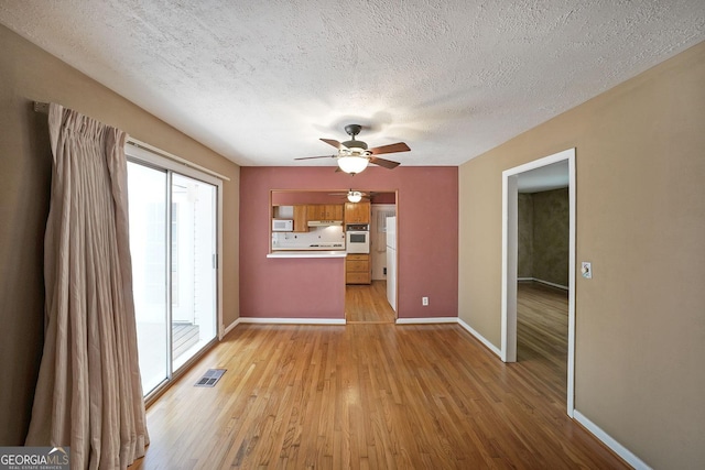 2394 Burch Cir NE, Brookhaven, GA 30319 - unfurnished living room featuring plenty of natural light, ceiling fan, light wood-type flooring, and a textured ceiling
