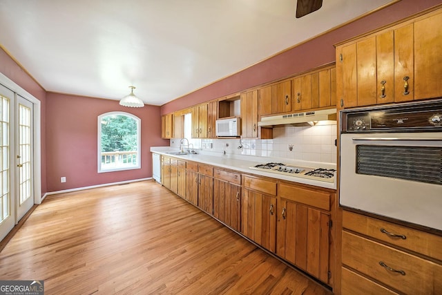 2394 Burch Cir NE, Brookhaven, GA 30319 - kitchen with white appliances, under cabinet range hood, a sink, brown cabinetry, and light wood-style floors