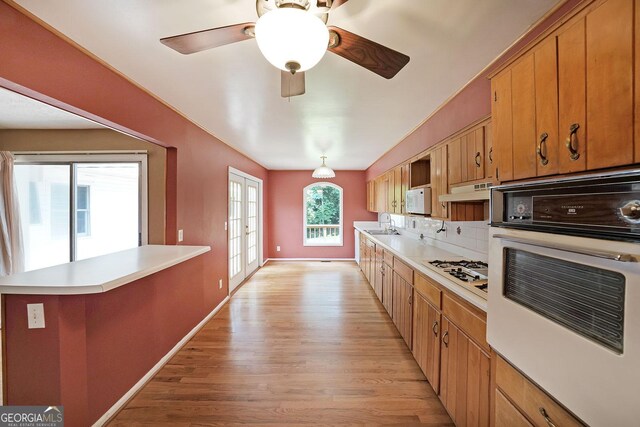 2394 Burch Cir NE, Brookhaven, GA 30319 - kitchen with white appliances, light wood-style flooring, light countertops, french doors, and brown cabinets