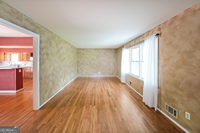 2394 Burch Cir NE, Brookhaven, GA 30319 - spare room with wood finished floors, healthy amount of natural light, a sink, and baseboards