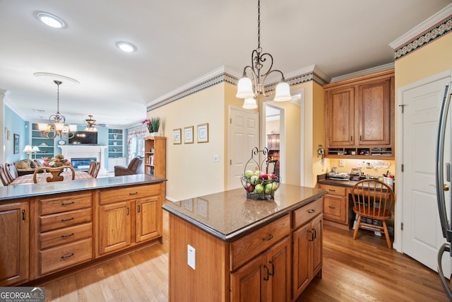 569 Fairway Dr, Woodstock, GA 30189 - kitchen with a chandelier, ornamental molding, a glass covered fireplace, a kitchen island, and brown cabinetry