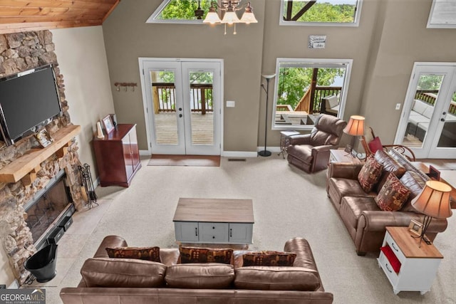 291 Thomas Dr, Eatonton, GA 31024 - carpeted living room featuring a stone fireplace, high vaulted ceiling, a chandelier, french doors, and baseboards
