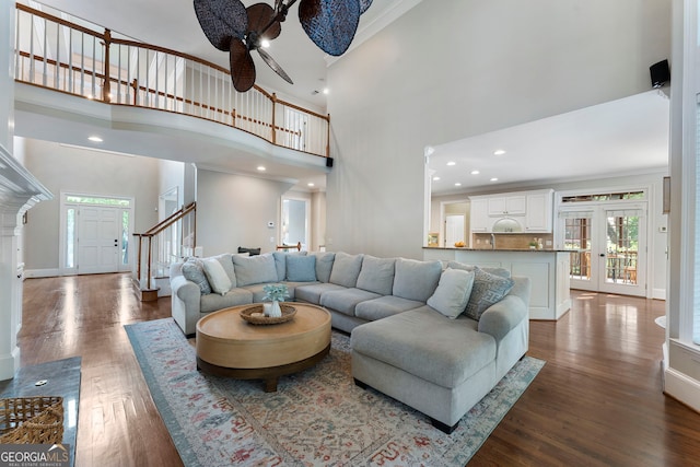 10135 High Falls Pointe, Johns Creek, GA 30022 - living room featuring dark wood-type flooring, a ceiling fan, a high ceiling, stairs, and crown molding