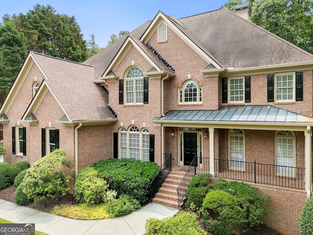 10135 High Falls Pointe, Johns Creek, GA 30022 - view of front of property featuring a chimney, brick siding, a shingled roof, a standing seam roof, and covered porch