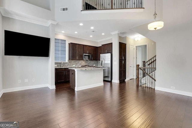 3005 Devoncroft St SE, Smyrna, GA 30080 - kitchen featuring appliances with stainless steel finishes, light countertops, dark brown cabinets, a kitchen island, and dark wood-style flooring