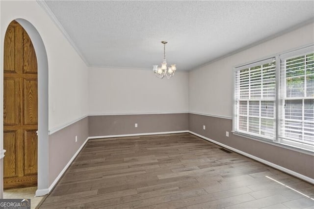 4956 Braeburn Trce NW, Acworth, GA 30102 - unfurnished dining area with wood finished floors, a textured ceiling, ornamental molding, a chandelier, and arched walkways