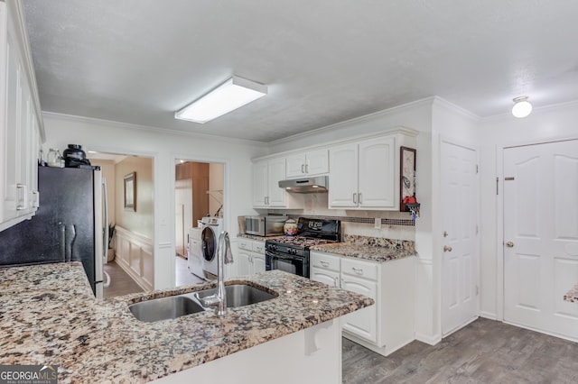 2005 Ashton Pointe Dr, Dacula, GA 30019 - kitchen with stainless steel appliances, under cabinet range hood, light stone countertops, washing machine and clothes dryer, and wood finished floors